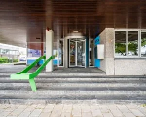 Ingang van een kantoorpand aan de van Heekstraat 15 in Schiedam met een opvallende groene trapleuning en een draaideur.