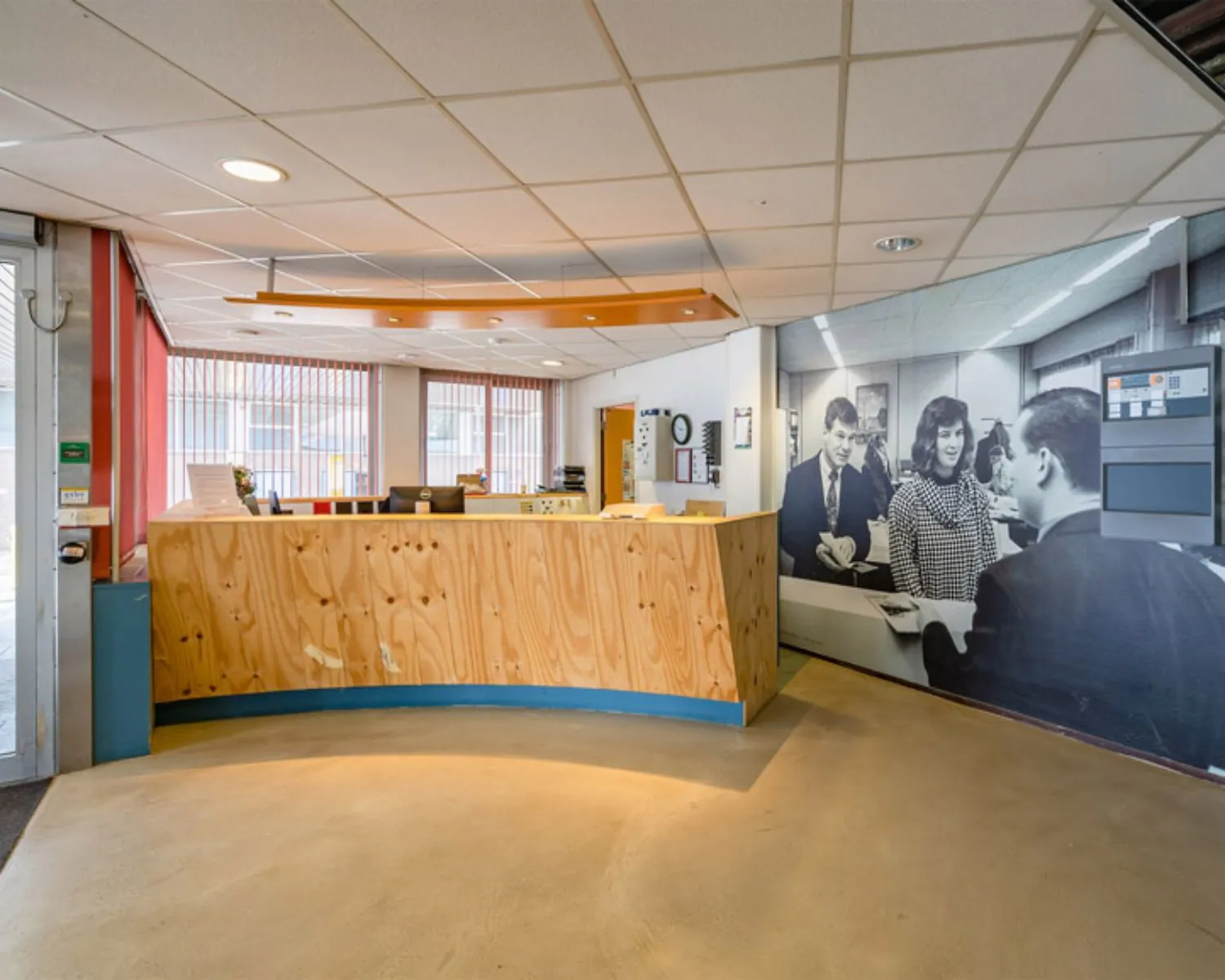 Receptiegebied van een kantoorruimte aan de Van Heekstraat 15 in Schiedam met houten balie en grote zwart-wit muurfoto.