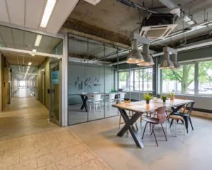 Moderne kantoorruimte aan de Van Heekstraat 15 in Schiedam met glazen vergaderruimte, industriële inrichting en grote ramen.