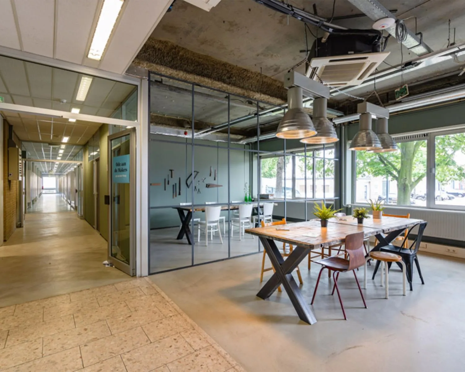 Moderne kantoorruimte aan de Van Heekstraat 15 in Schiedam met glazen vergaderruimte, industriële inrichting en grote ramen.