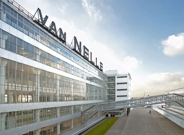 Buitenzijde van het Van Nelle Fabriek kantoorgebouw aan de Van Nelleweg 1 in Rotterdam met opvallende glazen gevel en loopbrug.