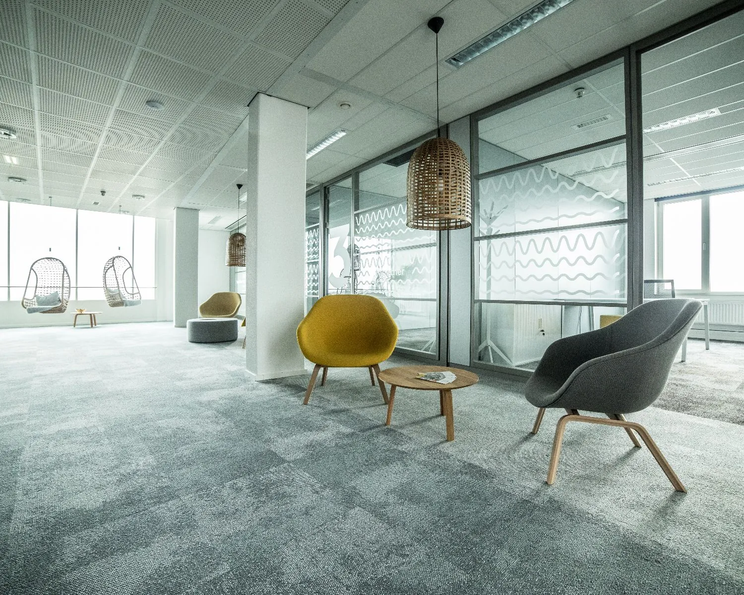 Moderne kantoorruimte aan de Wapenrustlaan 11-31 in Apeldoorn met glazen vergaderruimtes, loungefauteuils en hangstoelen.