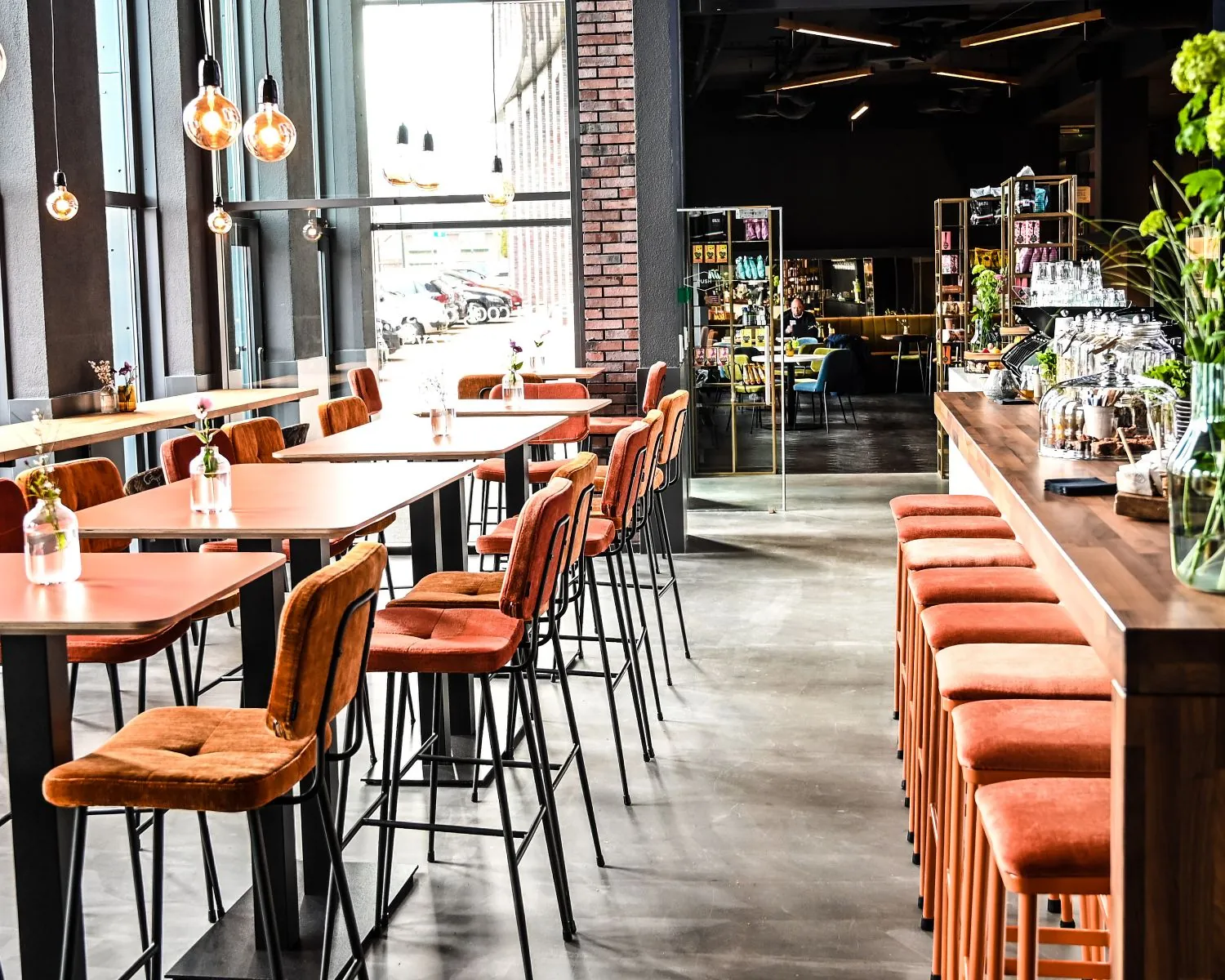 Moderne en sfeervolle kantoorruimte met hoge ramen, oranje barkrukken en tafels aan de Wapenrustlaan 11-31 in Apeldoorn.