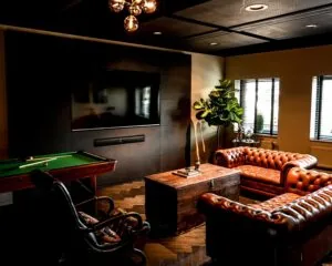 Stijlvol ingerichte kantoorruimte aan de Wapenrustlaan in Apeldoorn met leren chesterfieldbanken, een houten salontafel, een televisie en een pooltafel.