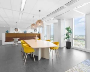 Moderne kantoorruimte te huur in Almere met grote ramen, een lichte vergadertafel en gele stoelen.
