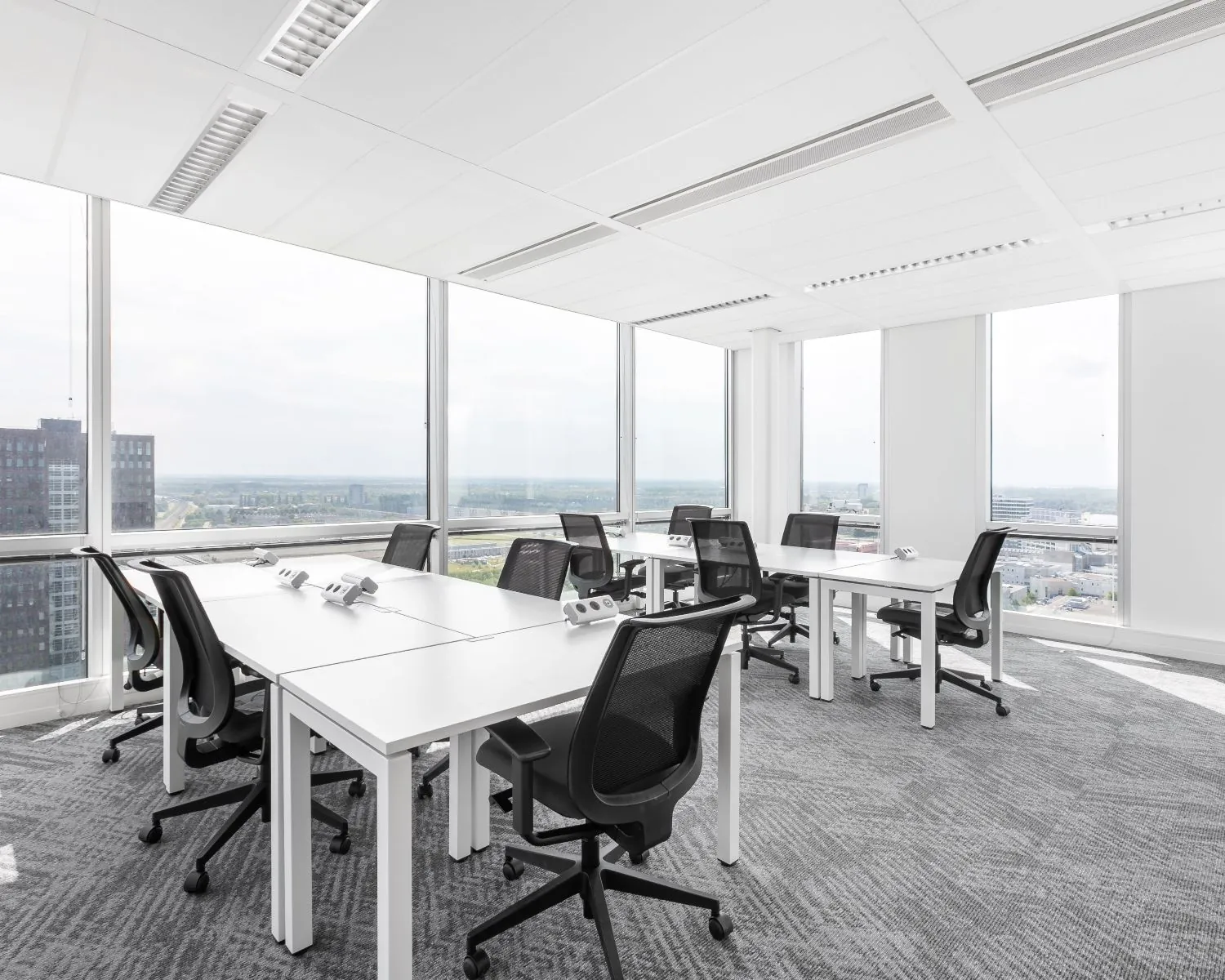 Moderne kantoorruimte met werkplekken en uitzicht op Almere vanaf het Mandela Plein.