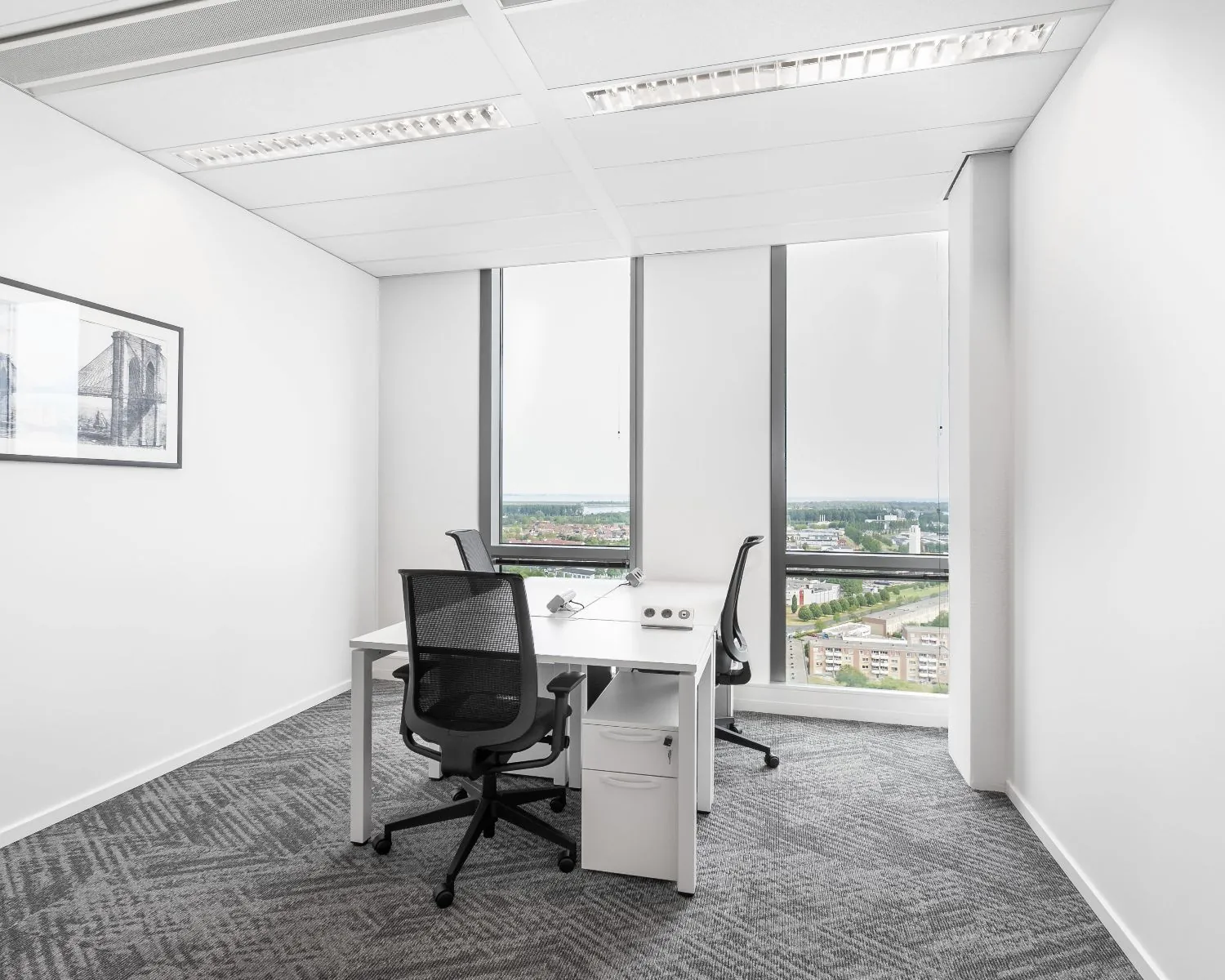 Moderne kantoorruimte met twee bureaus en uitzicht over Almere vanaf het Mandela Plein.