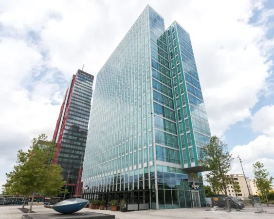 Moderne kantoortorens aan het Mandela Plein in Almere met glasgevels en omliggende stedelijke omgeving.