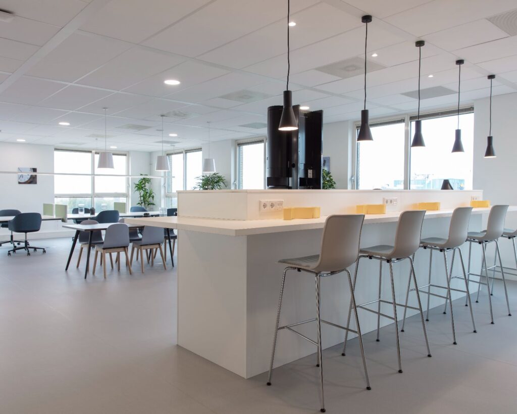 Moderne en lichte kantoorruimte aan de Van Heuven Goedhartlaan 13D in Amstelveen met hoge stoelen, werkplekken en hanglampen.
