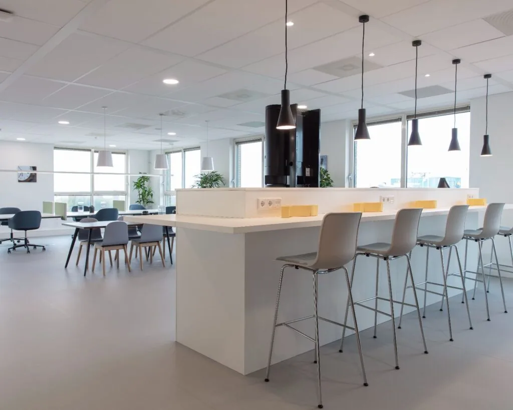 Moderne en lichte kantoorruimte aan de Van Heuven Goedhartlaan 13D in Amstelveen met hoge stoelen, werkplekken en hanglampen.