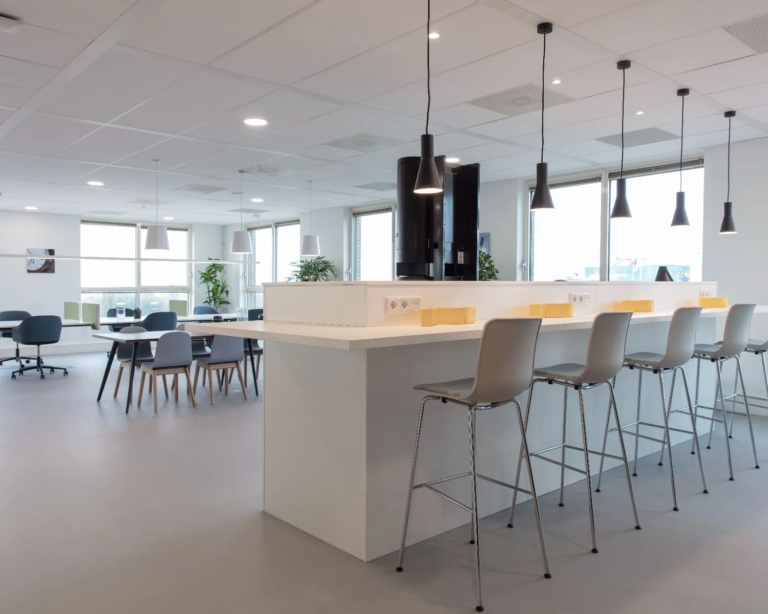 Moderne en lichte kantoorruimte aan de Van Heuven Goedhartlaan 13D in Amstelveen met hoge stoelen, werkplekken en hanglampen.