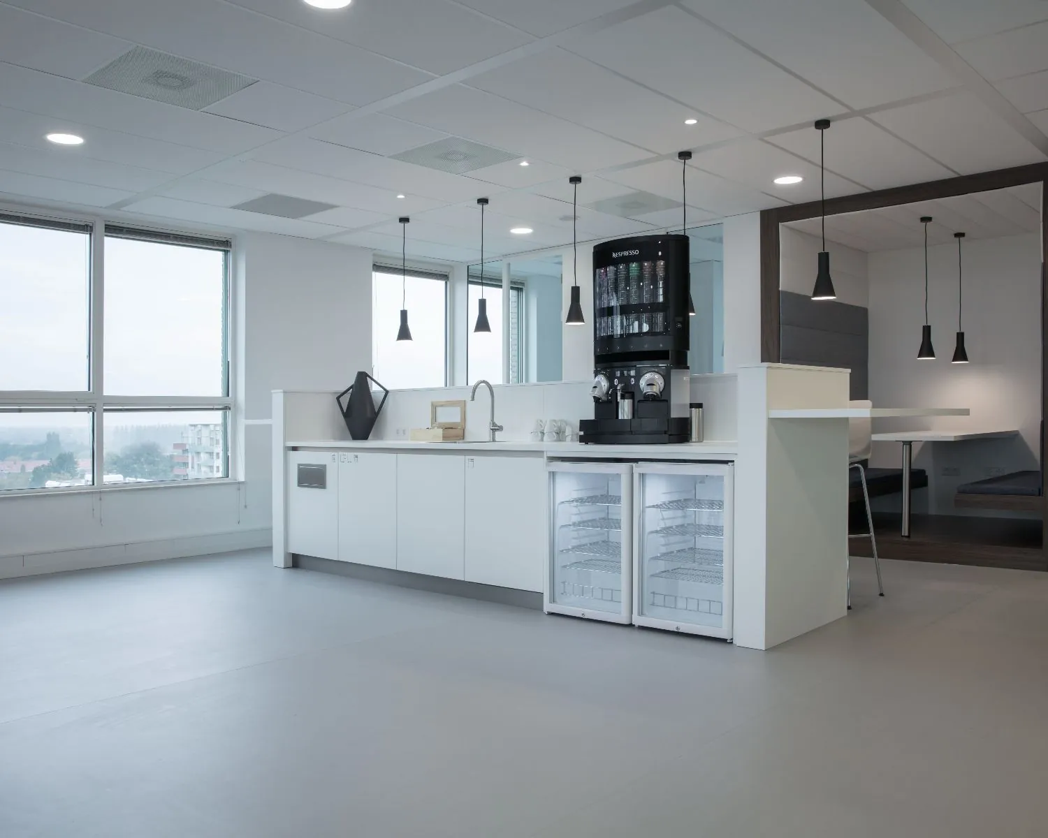 Moderne pantry met koffieautomaat en zitgedeelte in een kantoorruimte aan de Van Heuven Goedhartlaan 13D in Amstelveen.