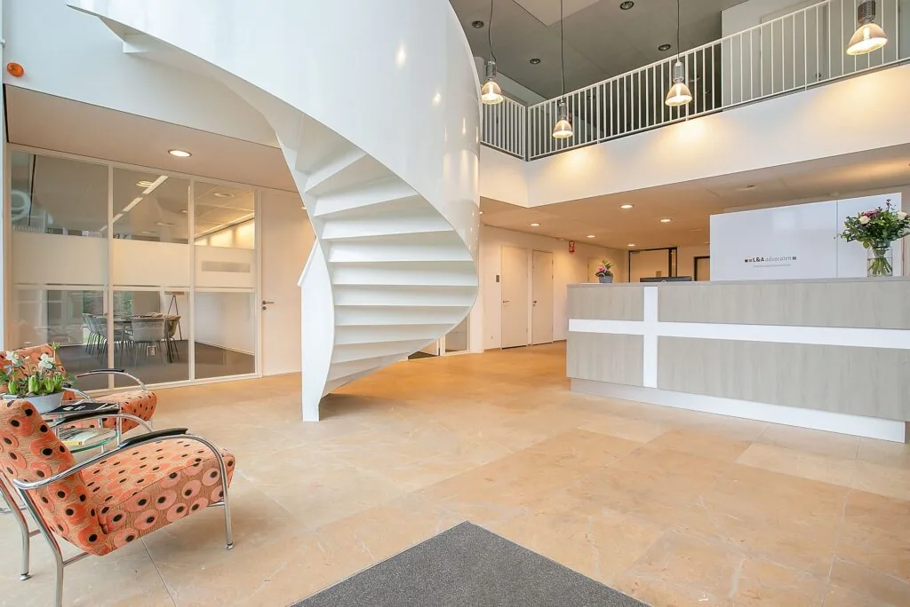 Moderne ontvangstruimte in kantoor aan de Cuserstraat 91 in Amsterdam met wenteltrap, balie en wachtruimte.
