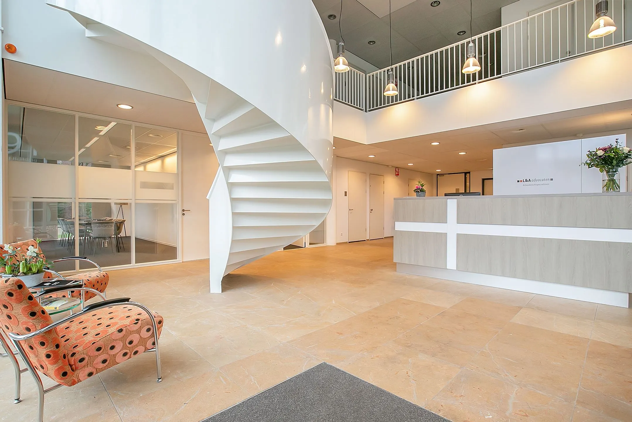 Moderne ontvangstruimte in kantoor aan de Cuserstraat 91 in Amsterdam met wenteltrap, balie en wachtruimte.