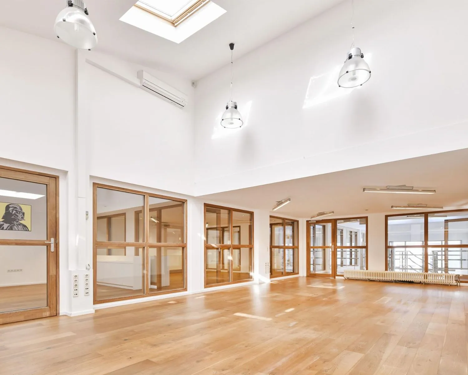 Moderne, lichte kantoorruimte met houten vloer en glazen scheidingswanden aan de Asterweg 20F in Amsterdam.