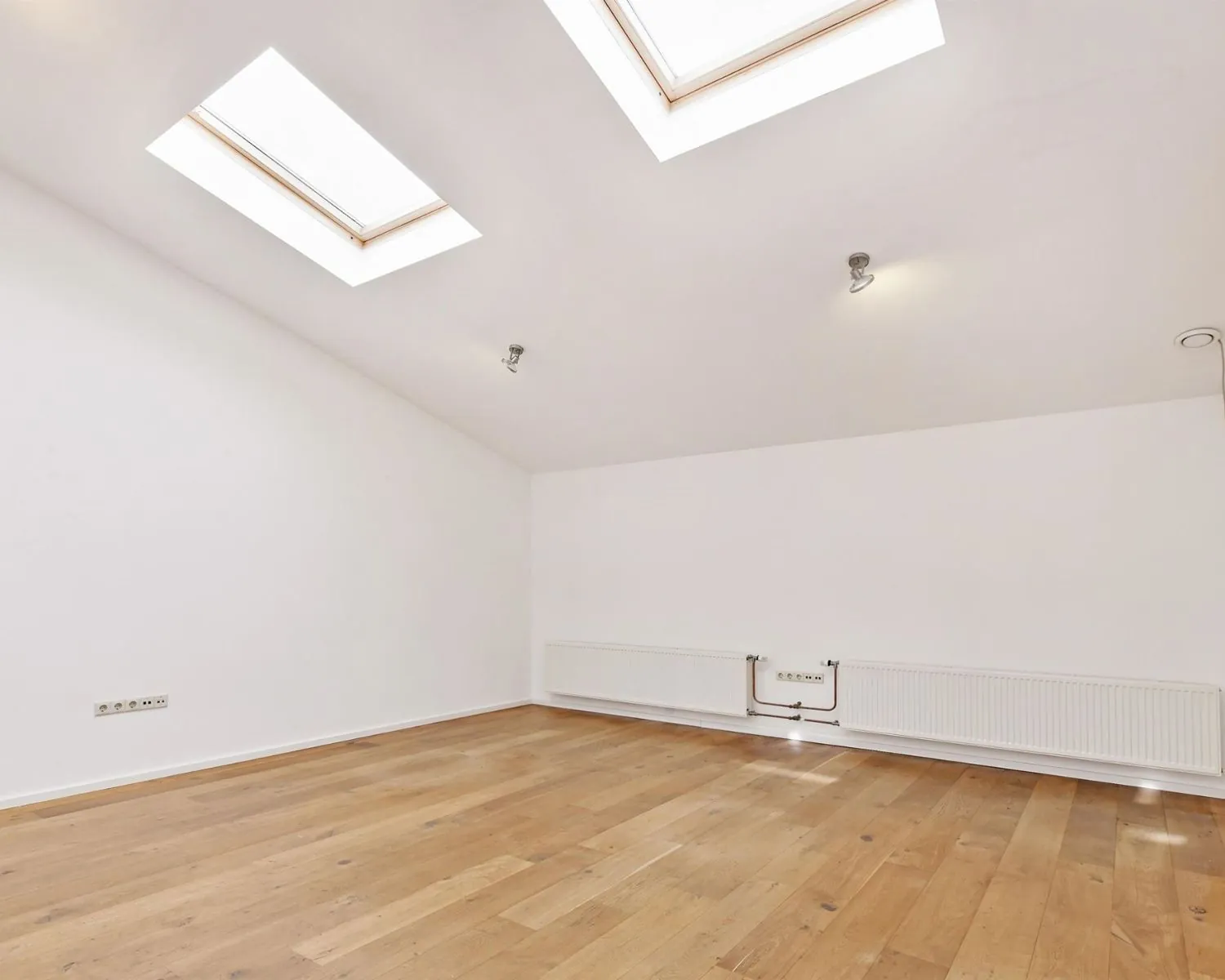 Lichte kantoorruimte aan de Asterweg 20F in Amsterdam met houten vloer, witte muren en twee dakramen.