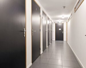Verlichte gang met meerdere zwarte deuren in een kantoorgebouw aan de Asterweg 20F in Amsterdam.