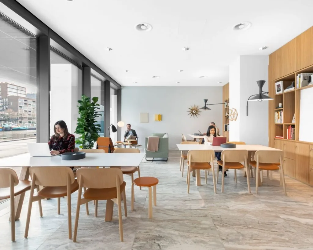 Moderne kantoorruimte in De Walvis aan de Grote Bickersstraat in Amsterdam met meerdere mensen werkend aan tafels en uitzicht op het water.