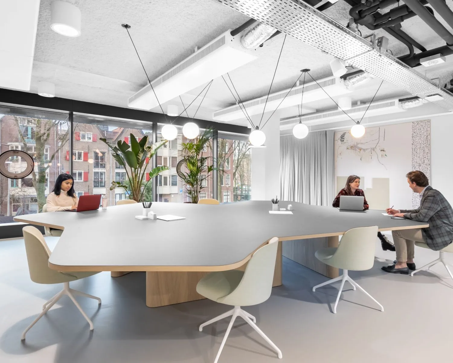 Moderne vergaderruimte in kantoorpand De Walvis aan de Grote Bickersstraat in Amsterdam, met grote tafel, designstoelen en uitzicht op de stad.