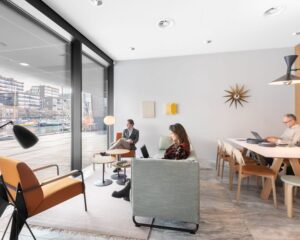 Moderne kantoorruimte in De Walvis aan de Grote Bickersstraat in Amsterdam met uitzicht op het water en mensen aan het werk.
