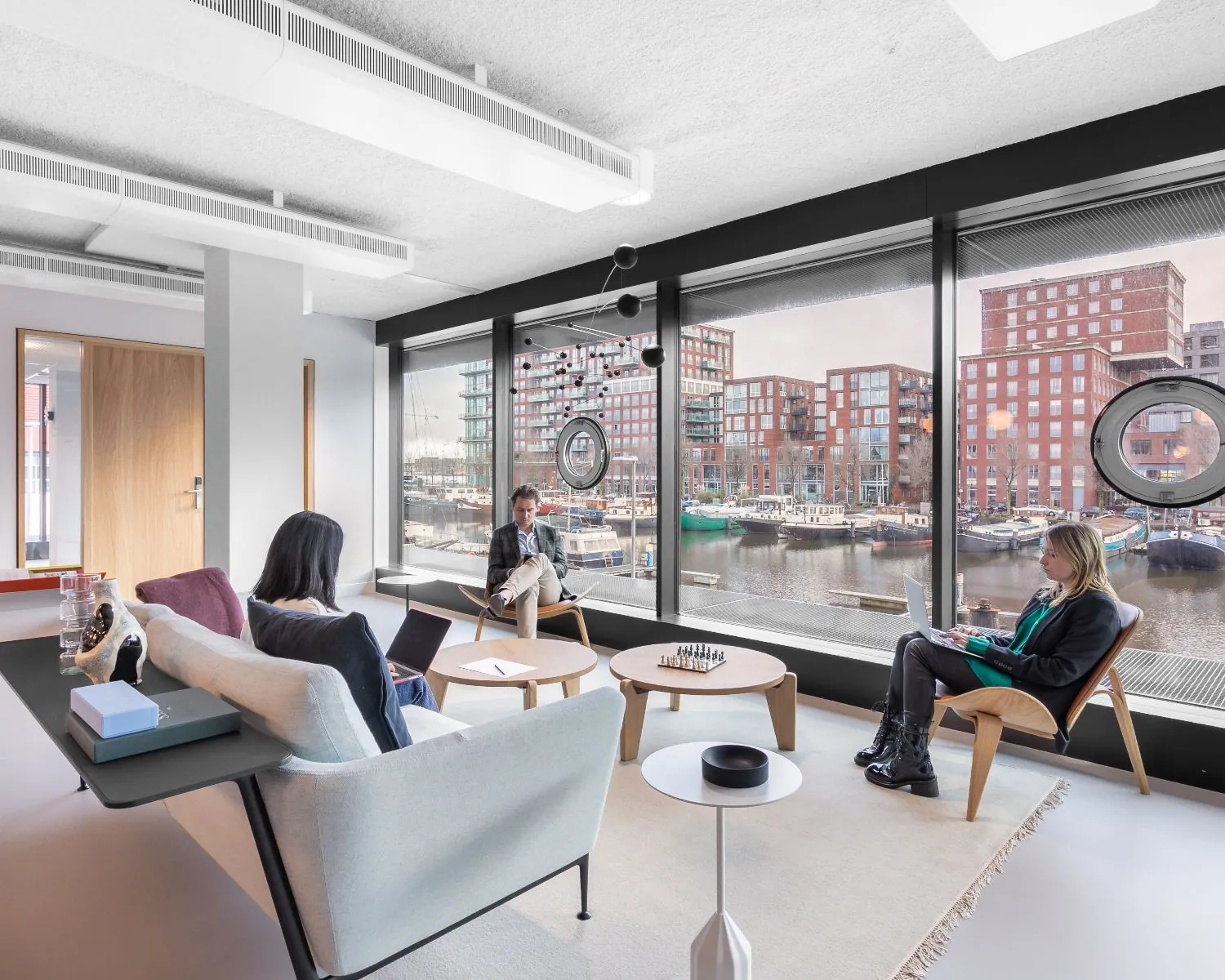 Moderne kantoorruimte in De Walvis aan de Grote Bickersstraat in Amsterdam met uitzicht op het water en drie werkende personen.