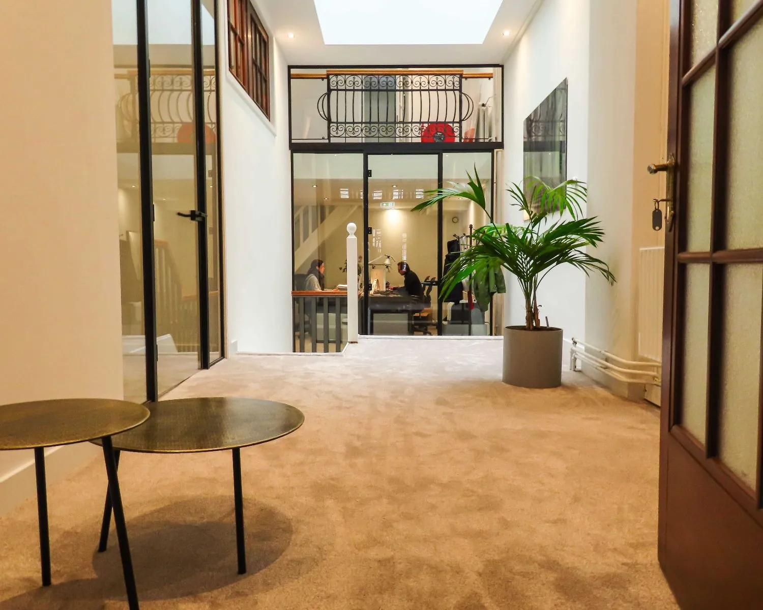 Moderne kantoorruimte aan de Herengracht 449a in Amsterdam met glazen deuren, een zithoek en uitzicht op een vergaderruimte.