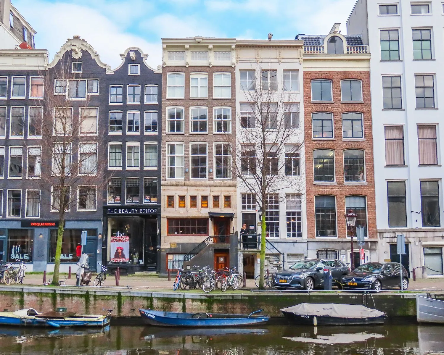 Gevelaanzicht van het kantoorpand aan de Herengracht 449a in Amsterdam met uitzicht op de gracht, fietsen en geparkeerde auto's.
