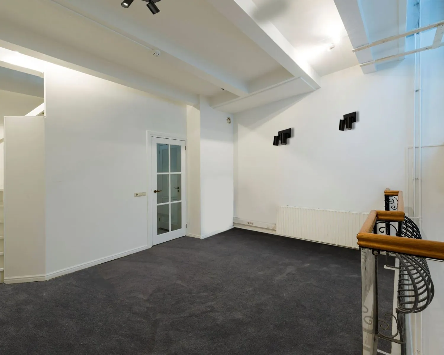 Moderne, lichte kantoorruimte met donker tapijt en glazen deur aan de Herengracht 449a in Amsterdam.