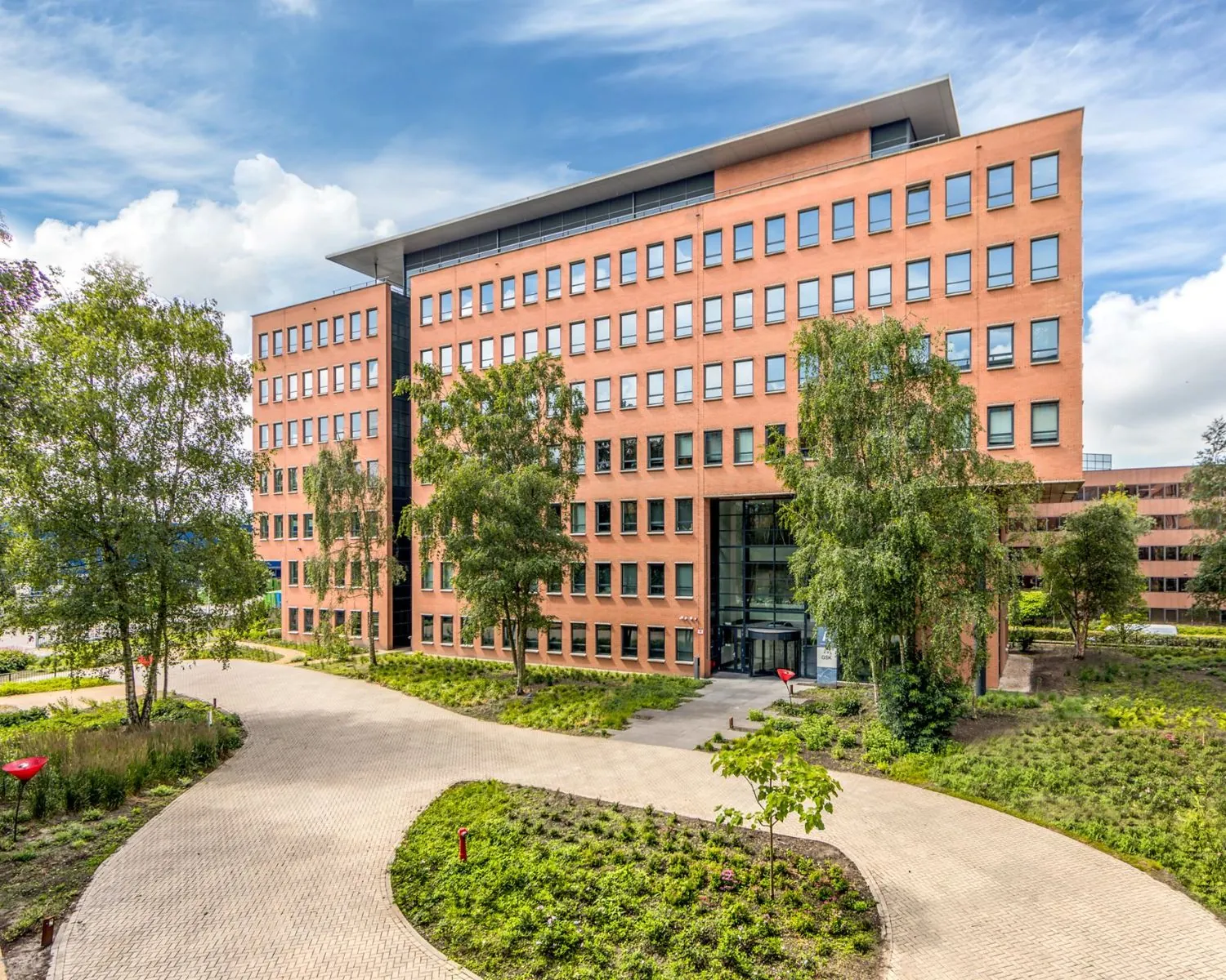 Modern kantoorgebouw aan de Hullenbergweg 81 in Amsterdam met een verzorgde groene omgeving.