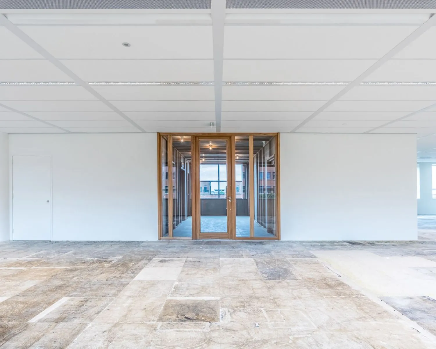 Leegstaande kantoorruimte met houten glaswand en uitzicht op de Hullenbergweg in Amsterdam.
