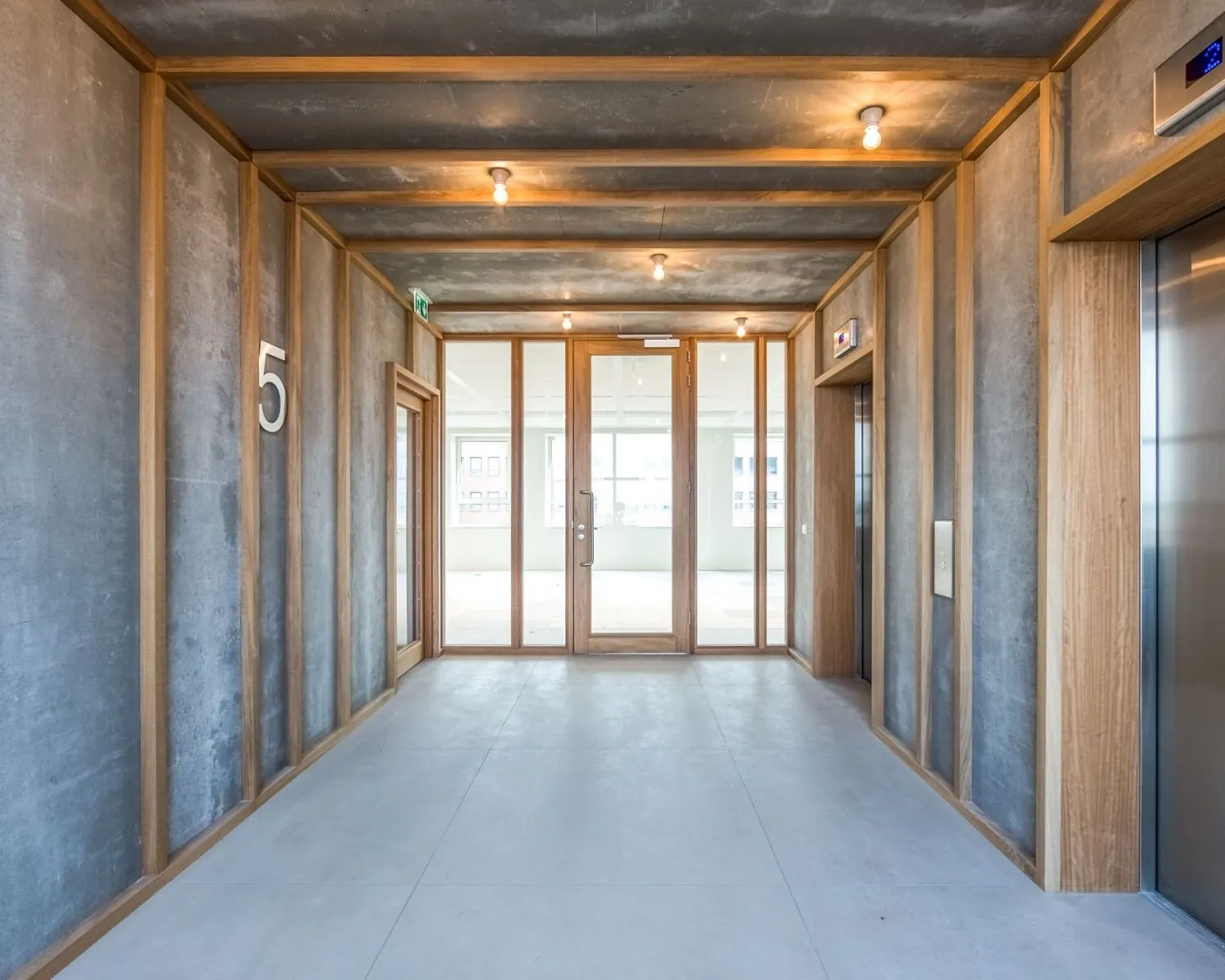 Moderne gang met liften en glazen deuren op de vijfde verdieping van een kantoorpand aan de Hullenbergweg 81 in Amsterdam.