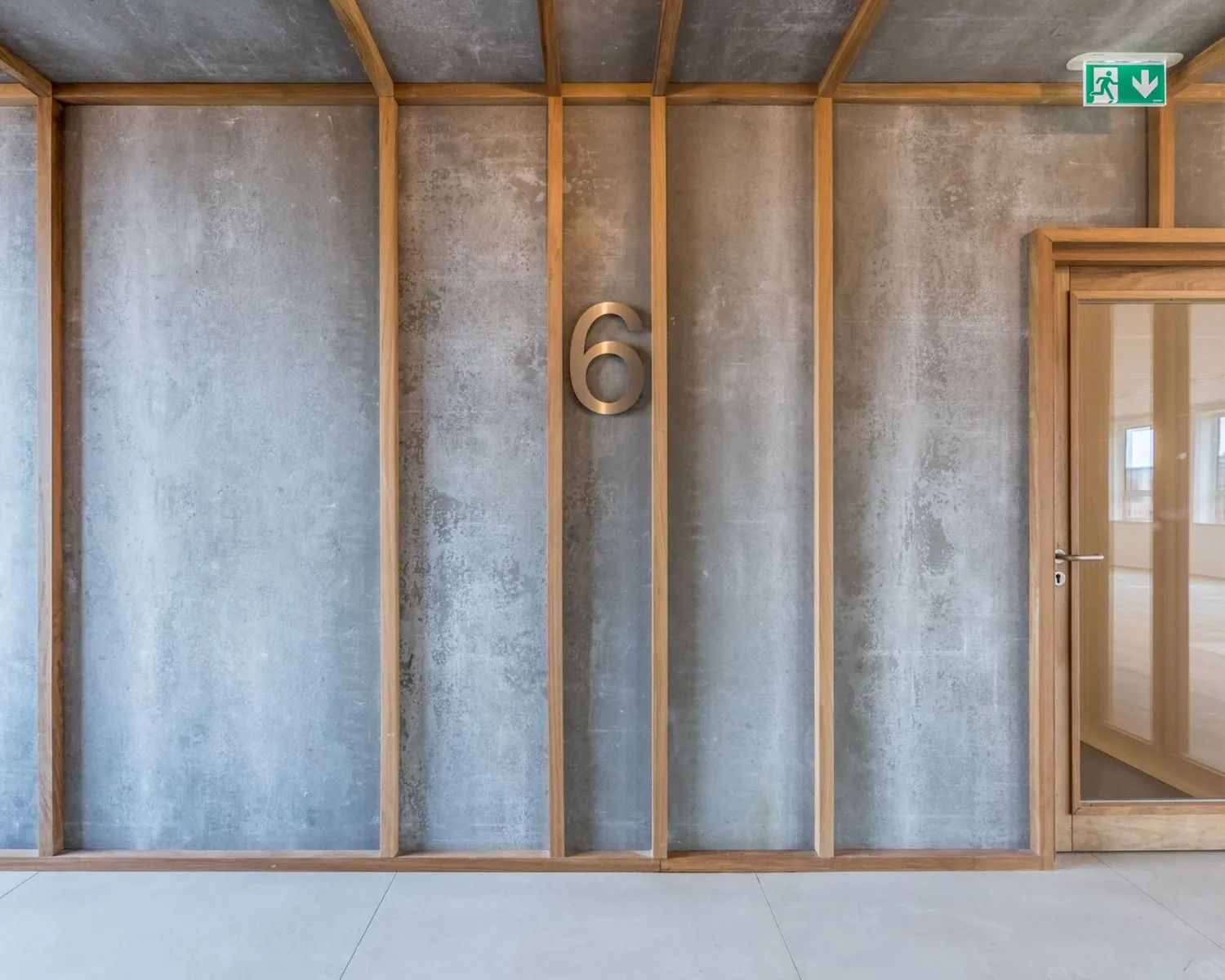 Industriële betonnen muur met houten afwerking, kamernummer 6 en glazen kantoordeur in Hullenbergweg 81, Amsterdam.