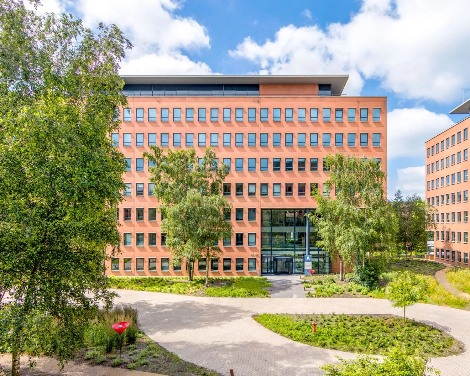 Voorzijde van een modern kantoorgebouw aan de Hullenbergweg 81 in Amsterdam, omringd door groen.