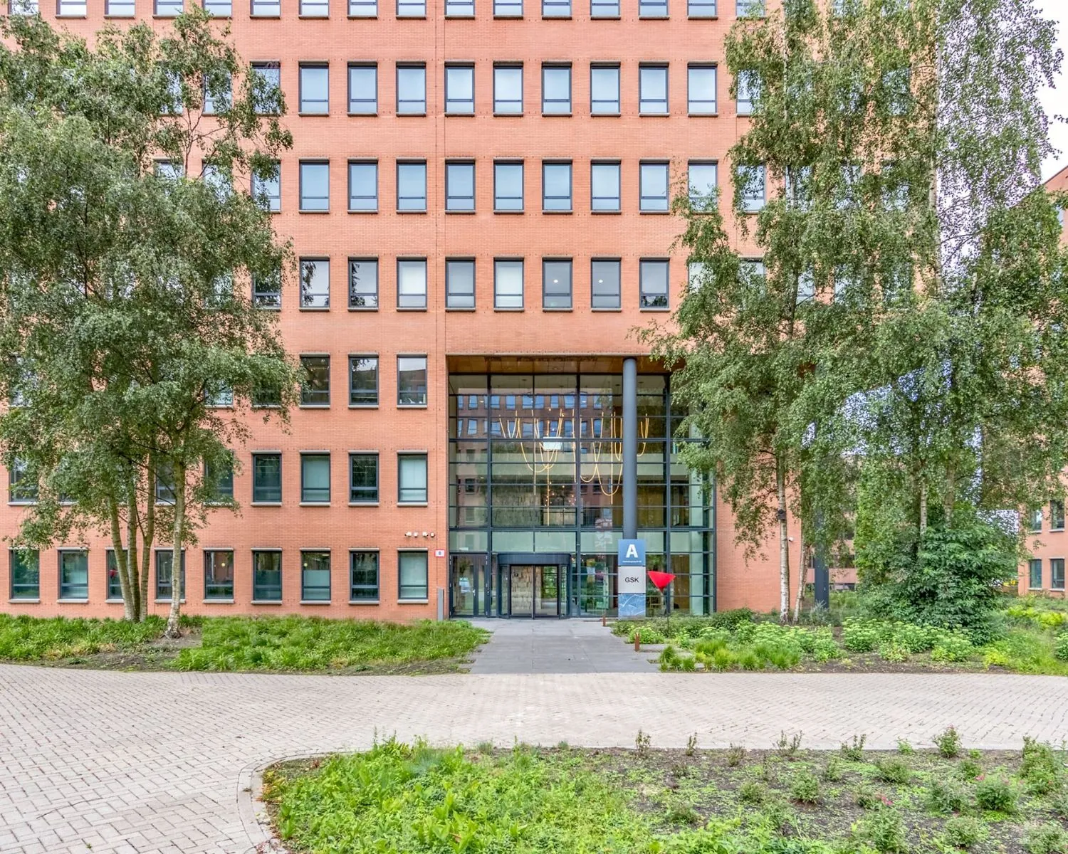 Voorgevel van een modern kantoorgebouw aan de Hullenbergweg 81 in Amsterdam met glazen entree en omliggend groen.