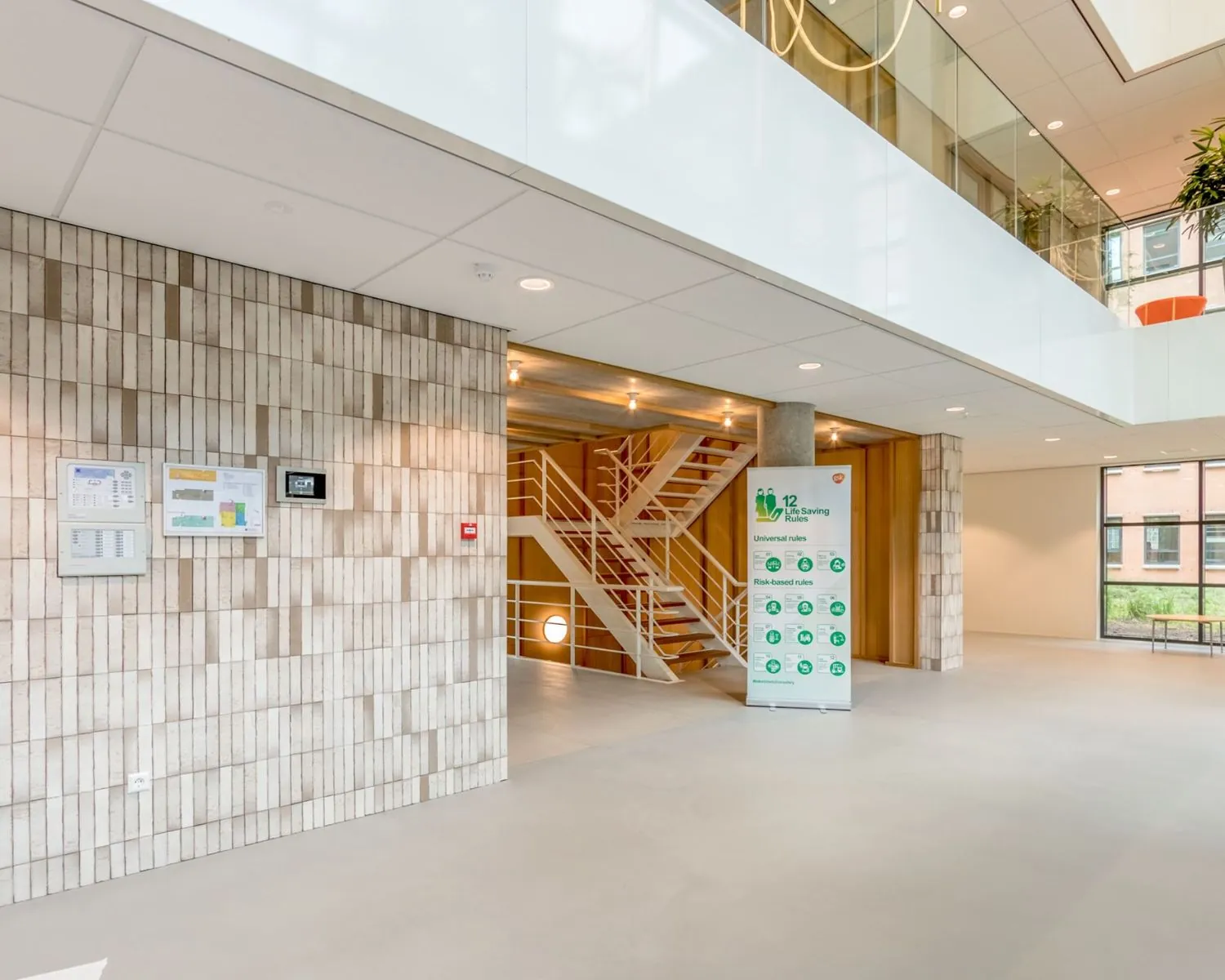 Moderne entreehal van een kantoorruimte aan de Hullenbergweg 81 in Amsterdam met trap, informatieborden en natuurlijk licht.