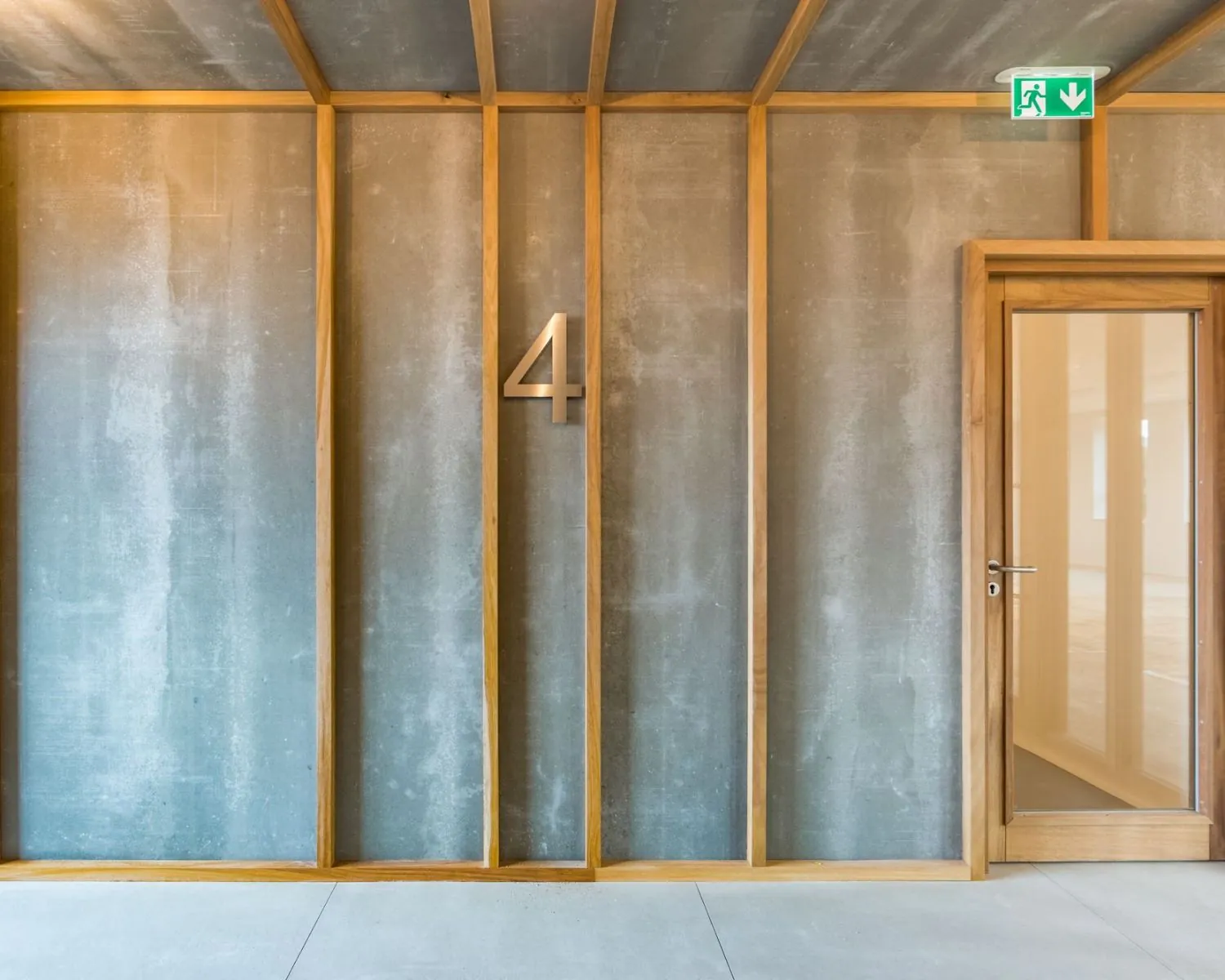 Moderne kantoorverdieping met betonnen wand, houten afwerking, kamer-nummer 4 en glazen deur op Hullenbergweg 81 in Amsterdam.