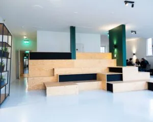 Moderne kantoorruimte aan de Prins Hendrikkade in Amsterdam met een houten tribunebank en een zithoek op de achtergrond.