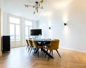 Moderne vergaderruimte met gele stoelen, een zwart vergadertafel en grote ramen in een kantoor aan de Prins Hendrikkade in Amsterdam.