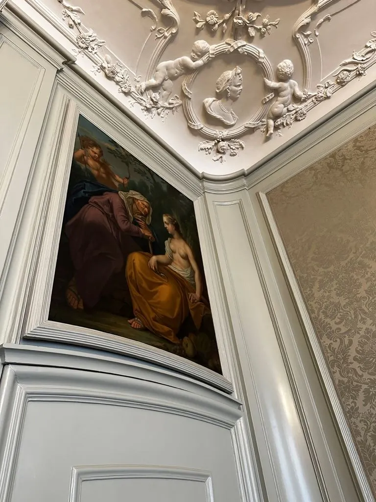 Sierlijk plafond met stucwerk en een klassiek schilderij in een monumentaal kantoor aan het Singel 126-130 in Amsterdam.