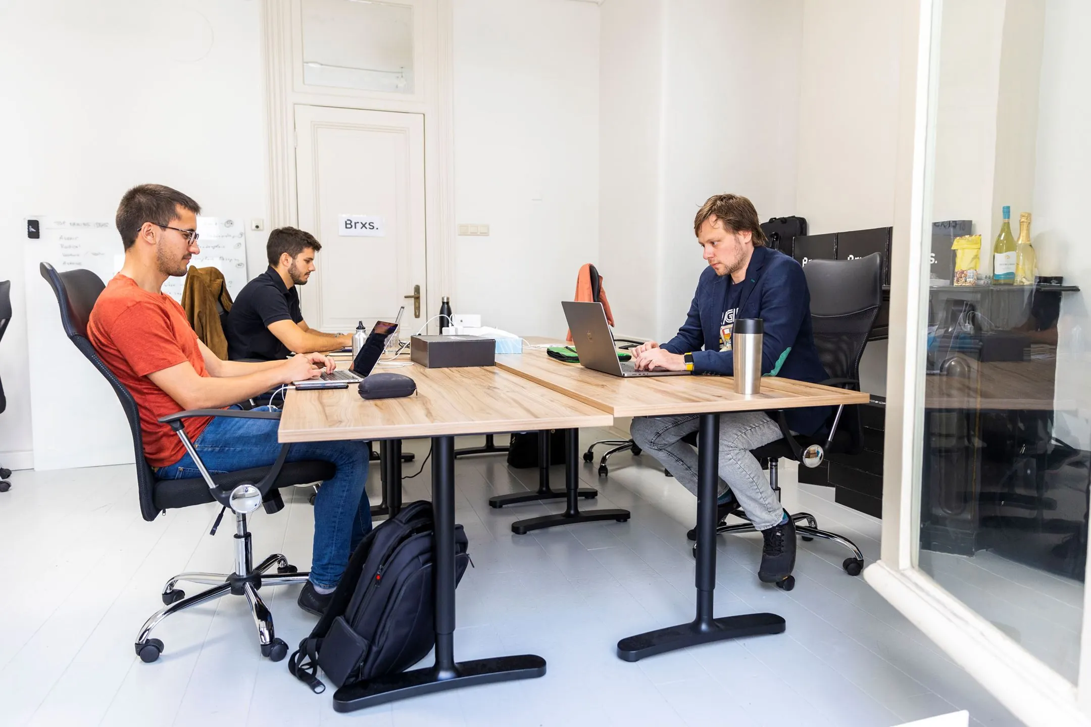 Drie personen werken op laptops in een moderne kantoorruimte aan de Singel 126-130 in Amsterdam.