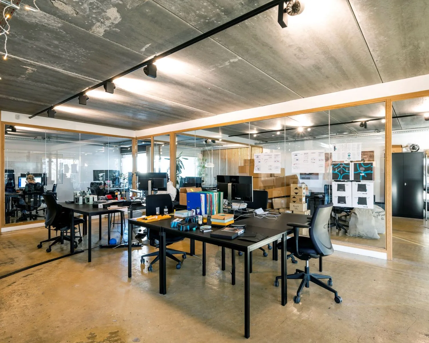 Moderne kantoorruimte met werkplekken, glazen wanden en industriële uitstraling aan de Vliegtuigstraat in Amsterdam.