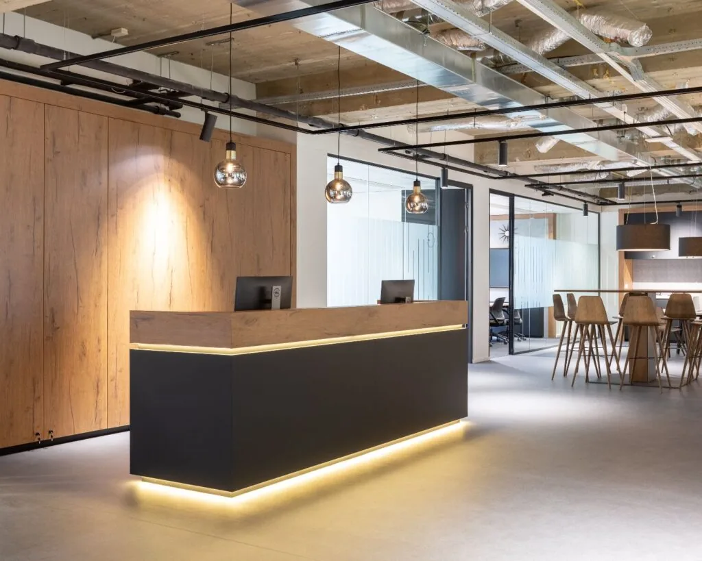 Moderne kantoorruimte in Amsterdam Weerdestein 97 met houten receptiebalie, designverlichting en glazen vergaderruimtes.