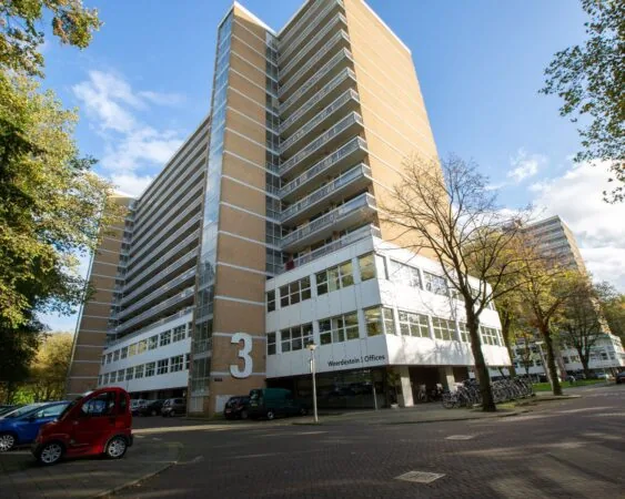 Hoog kantoorgebouw aan de Weerdestein 97-9 in Amsterdam met geveltekst "Weerdestein Offices" en parkeergelegenheid.
