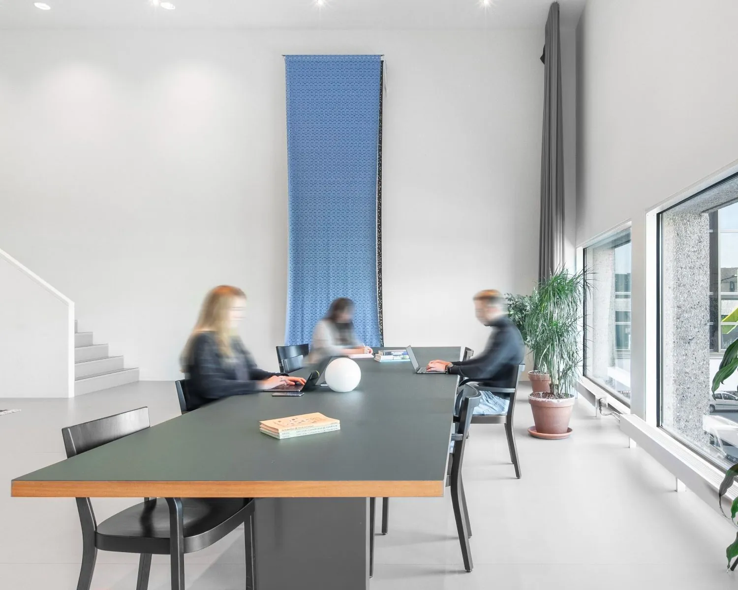 Moderne kantoorruimte aan de Haarlemmerweg 331 in Amsterdam met grote ramen, strakke inrichting en mensen die aan een lange tafel werken.