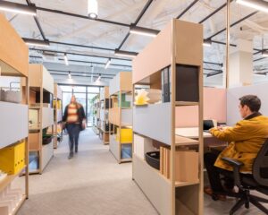 Moderne flexwerkplek met open kasten en werkende mensen in een kantoorruimte aan de Haarlemmerweg 331 in Amsterdam.