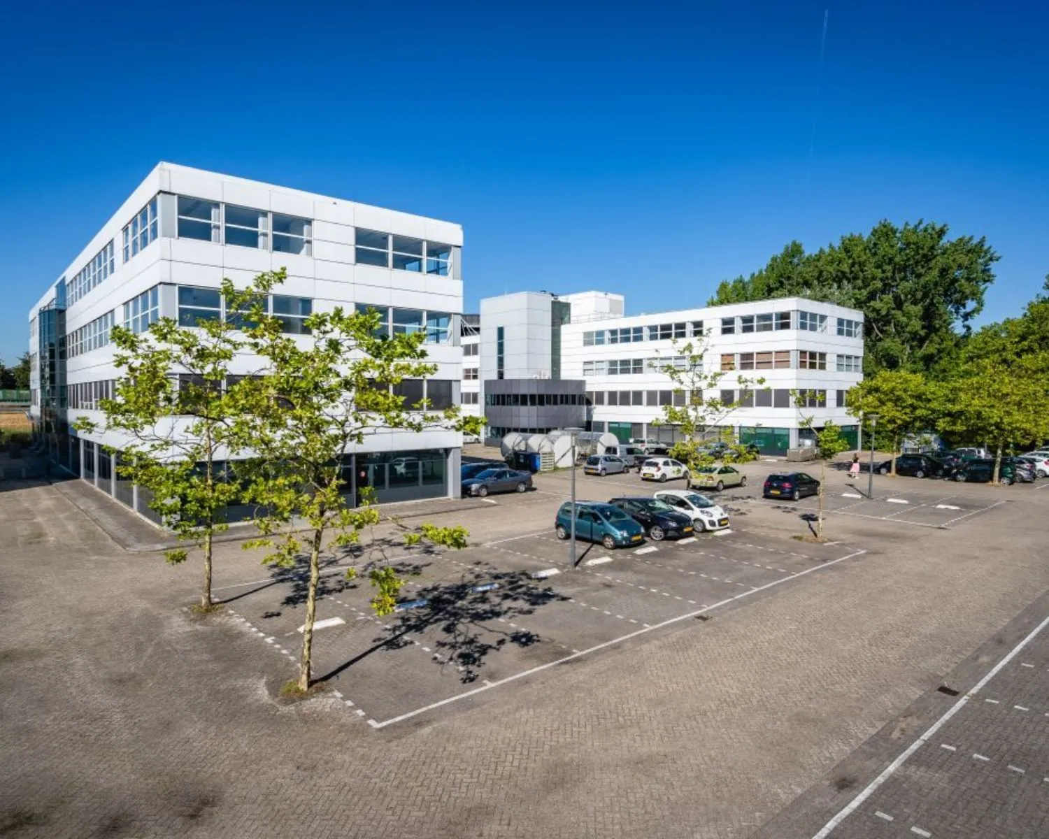 Wit kantoorgebouw met parkeergelegenheid aan de Olof Palmeweg 12-18 in Delft op een zonnige dag.