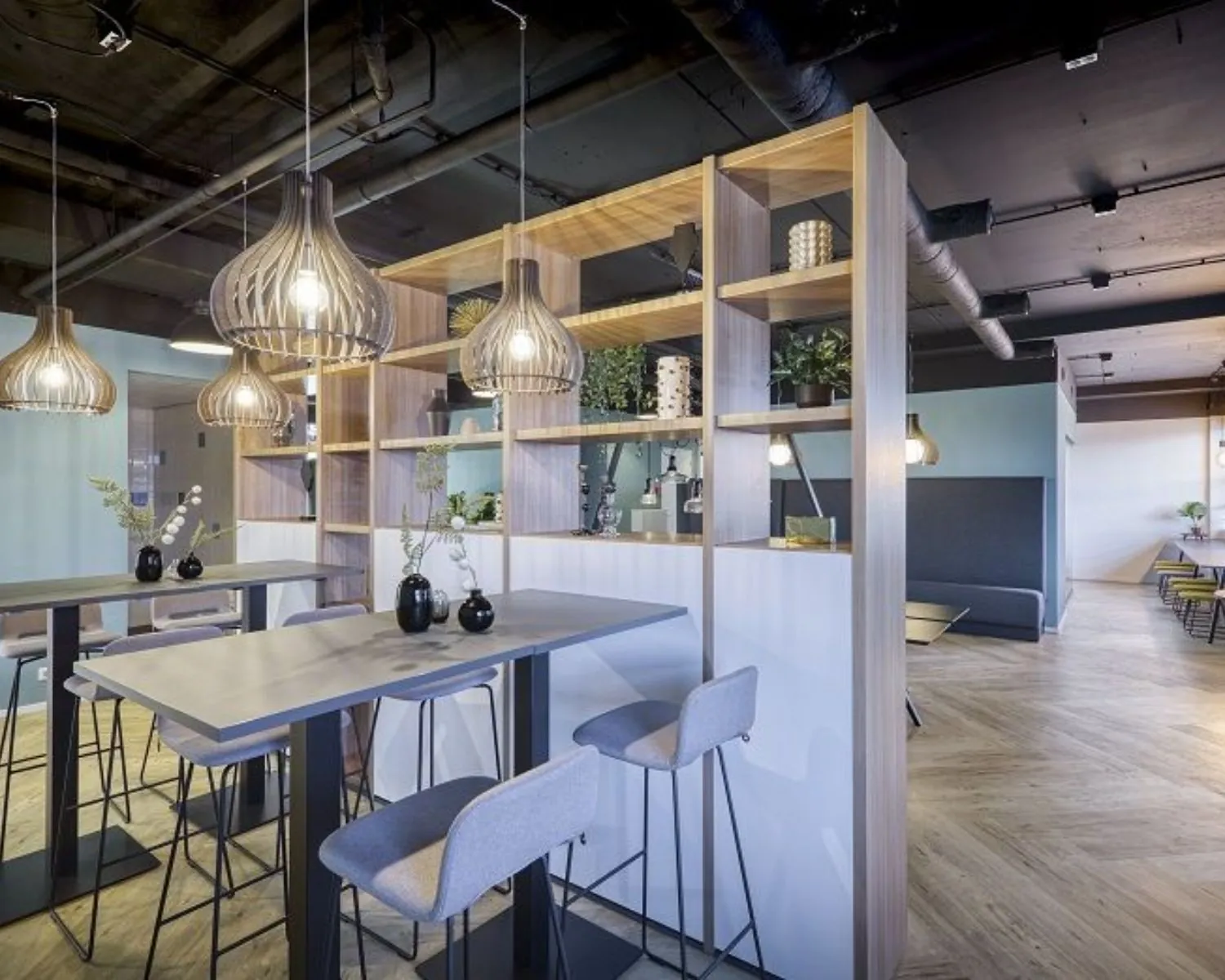 Moderne en sfeervolle kantoorruimte met hoge tafels, designverlichting en een open houten kast in Delft aan de Olof Palmeweg.