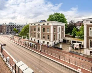 Klassiek kantoorpand aan de Alexanderstraat in Den Haag met uitzicht op trambaan en bushalte.