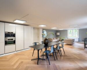 Moderne kantoorruimte in Den Haag met open keuken, vergadertafel en zithoek met veel natuurlijk licht.