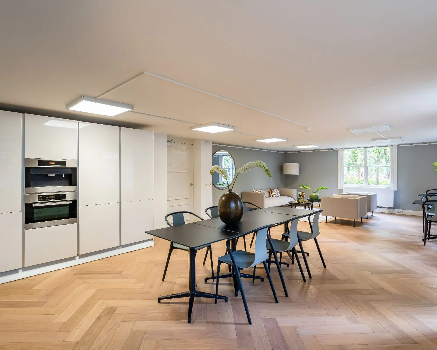 Moderne kantoorruimte in Den Haag met open keuken, vergadertafel en zithoek met veel natuurlijk licht.